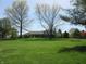 Vast backyard shows rear of home and landscaping with lush trees and open grass at 4166 Cobblestone Way, Greenwood, IN 46143
