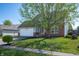 Charming home with a lush green lawn, mature tree, brick accents, and an attached two car garage at 419 Old Glory Dr, Greenfield, IN 46140