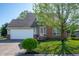 Charming home with a lush green lawn, mature tree, brick accents, and an attached two car garage at 419 Old Glory Dr, Greenfield, IN 46140