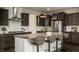 A modern kitchen with dark cabinets, stainless steel appliances, granite countertops, and seating at the island at 4428 Voyageur Way, Carmel, IN 46074