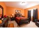 Bedroom featuring an orange accent wall, hardwood floors, and black furniture at 5251 Ladywood Bluff Pl, Indianapolis, IN 46226
