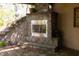 Stylish outdoor stone fireplace with stainless steel front set in stone platform on a tiled patio under a pergola at 5251 Ladywood Bluff Pl, Indianapolis, IN 46226