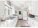 Bright galley kitchen with white cabinetry, stainless steel sink and appliances, and neutral tile flooring at 5747 Allisonville Rd, Indianapolis, IN 46220