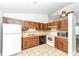 Cozy kitchen featuring oak cabinets, tile backsplash, white appliances, and a tile floor at 5855 La Fleur Ct, Indianapolis, IN 46237