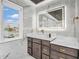 Bright bathroom featuring marble walls, custom dark cabinets with gold hardware, and a modern, lighted mirror at 6044 Shallow Crk Ln, Indianapolis, IN 46237