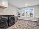 Well-lit laundry room featuring a modern washer and dryer set, tiled flooring, and ample natural light from large windows at 6044 Shallow Crk Ln, Indianapolis, IN 46237