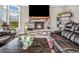 Living room featuring a stone fireplace, flat screen TV, view of the lush outdoors, and a large leather sofa at 6044 Shallow Crk Ln, Indianapolis, IN 46237