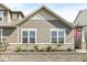 Home featuring decorative siding, landscaping, a stone retaining wall, and an American flag at 7092 Cherry Creek Blvd, Carmel, IN 46033