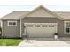 Attached two-car garage with paneled door and exterior lights and a small patio set to the side at 7092 Cherry Creek Blvd, Carmel, IN 46033