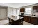 Well-lit kitchen with dark cabinets, a central island with seating, and stainless steel appliances at 7195 E Rising Sun S Cir, Camby, IN 46113