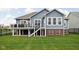 Rear exterior of home with a spacious deck, well-manicured lawn and stairs leading to the yard at 7450 Cassilly Ct, Indianapolis, IN 46278