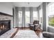 Comfortable living area with a stone fireplace, plush armchair, and large windows providing natural light at 7450 Cassilly Ct, Indianapolis, IN 46278