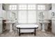 This bathroom features dual sinks, a free-standing tub, tile floors, and a large window providing natural light at 7845 Allisonville Rd, Indianapolis, IN 46250