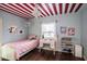 This bedroom features a small bed with a pink cover, hardwood floors, and a built in desk at 7845 Allisonville Rd, Indianapolis, IN 46250