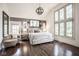 This main bedroom features a large bed with a sitting chair, hardwood floors, and lots of natural light at 7845 Allisonville Rd, Indianapolis, IN 46250