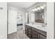Bright bathroom featuring a double sink vanity with stylish fixtures and an open doorway to the Primary bedroom at 7901 Apalachee Dr, Indianapolis, IN 46217