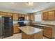 Cozy kitchen featuring oak cabinets, black appliances, a center island, and neutral paint at 8888 N White Tail N Trl, McCordsville, IN 46055