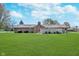 Well-maintained backyard with green lawn and brick house, plus wood fence, trees, and blue skies at 990 Broadway N Dr, Plainfield, IN 46168