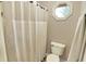 Bright bathroom with a white shower curtain, toilet and a octagon-shaped window at 10715 Hamilton Pass, Fishers, IN 46037