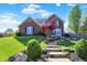 Charming brick home with landscaped front yard, stone steps, and blooming trees at 10715 Hamilton Pass, Fishers, IN 46037