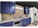 Wet bar features blue cabinets, granite counters, stone backsplash, and a wine fridge at 10715 Hamilton Pass, Fishers, IN 46037