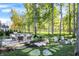 Lush backyard featuring outdoor kitchen, fireplace with Adirondack chairs and mature trees at 10725 Holliday Farms Blvd, Zionsville, IN 46077