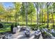 Lush backyard featuring outdoor kitchen, fire pit with Adirondack chairs and mature trees at 10725 Holliday Farms Blvd, Zionsville, IN 46077