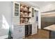 A well-lit bar area with custom cabinets, a wine fridge, and a decorative backsplash at 10725 Holliday Farms Blvd, Zionsville, IN 46077