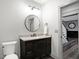 This bathroom features a dark wood vanity, a marble countertop, a round mirror, and modern light fixtures at 10725 Holliday Farms Blvd, Zionsville, IN 46077