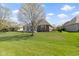A green lawn and brick home with outdoor patio are featured under a bright, partly cloudy sky at 10911 Innisbrooke Ln, Fishers, IN 46037