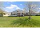A manicured lawn features a brick home with a patio, set under a partly cloudy sky at 10911 Innisbrooke Ln, Fishers, IN 46037