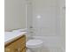 Clean bathroom featuring a white tiled shower-tub combination, toilet and wood vanity at 10911 Innisbrooke Ln, Fishers, IN 46037