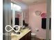 A pink bathroom featuring a double vanity, a toilet, mirrors and decorative floral wall art at 11555 Ross Common Dr, Indianapolis, IN 46229