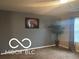 Spacious living room with a large window, wall-mounted TV and decorative tree at 11555 Ross Common Dr, Indianapolis, IN 46229