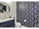 A half bathroom with decorative wallpaper, gold fixtures, and a blue vanity at 1317 Spann Ave, Indianapolis, IN 46203