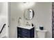 A half bathroom featuring a blue vanity, round mirror, and toilet, with a staircase to the side at 1317 Spann Ave, Indianapolis, IN 46203