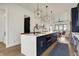 An open-concept kitchen with navy cabinets, quartz countertops, stainless steel appliances, and a large island with barstools at 1317 Spann Ave, Indianapolis, IN 46203