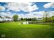 Picturesque backyard with a pond view, surrounded by a well-manicured lawn and charming picket fence, creating a serene oasis at 13331 Grouse Point Trl, Carmel, IN 46033