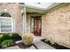 Close-up of the front entrance featuring a brick facade, lush landscaping, and a modern front door for a welcoming feel at 13331 Grouse Point Trl, Carmel, IN 46033
