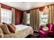 Red bedroom featuring three windows, a fuchsia chair, and a soft inviting bed at 1733 N Spencer Ave, Indianapolis, IN 46218