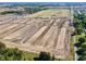 Aerial view of a large-scale residential development site showcasing graded lots, road construction and surrounding greenery at 196 Aster Way, Greenfield, IN 46140