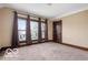 Bright bedroom with three windows, carpet flooring, and a dark wood door at 2001 Hoyt Ave, Indianapolis, IN 46203