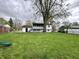 Spacious backyard with lush green grass, a large shade tree, and a charming patio area at 210 Prairie Pkwy, Brownsburg, IN 46112