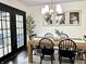 Dining room showcasing a wooden table set for six, chandelier, and door to the outside at 210 Prairie Pkwy, Brownsburg, IN 46112