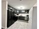 Modern kitchen featuring sleek black cabinets, stainless steel appliances, and elegant gray tile flooring at 210 Prairie Pkwy, Brownsburg, IN 46112