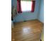 Small blue bedroom featuring hardwood flooring and window with red curtains at 2141 N Cole St, Indianapolis, IN 46224