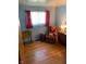 Cozy bedroom with wood floors, a window with red curtains, and an assortment of furniture at 2141 N Cole St, Indianapolis, IN 46224