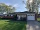Charming ranch-style home with brick accents, a manicured lawn, and an attached garage at 2141 N Cole St, Indianapolis, IN 46224