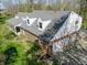 An aerial view shows the brick home, gray roof, attached garage, and surrounding lush greenery at 2394 W 600 S, New Palestine, IN 46163