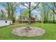 Backyard with a fire pit surrounded by trees and wooden posts with string lights at 2920 N Buck Creek Rd, Greenfield, IN 46140